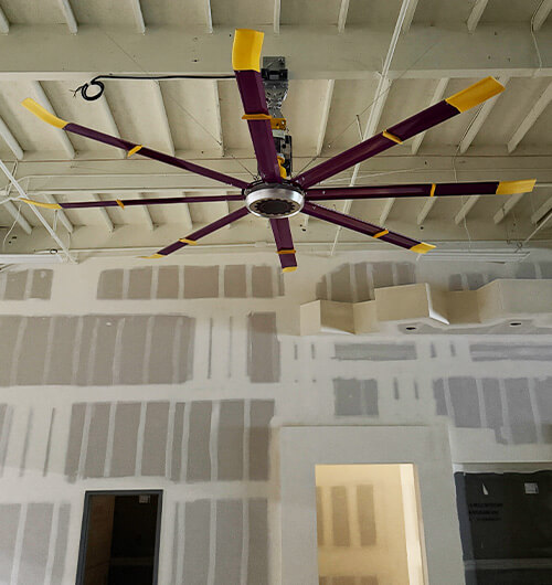 HVLS ceiling fan installed in Planet Fitness gym during construction to improve airflow and ventilation in Southern California